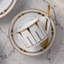 White teacup with gold accents on a matching saucer on a marble surface
