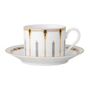 White cup and saucer with gold and black geometric design on a white background
