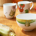 Ceramic bowls and mugs with cartoon character design on a wooden surface.